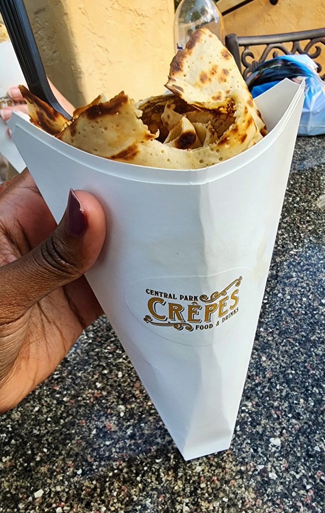 A crepe in its white paper holder labeled with the name of the stand, "Central Park Crepes."