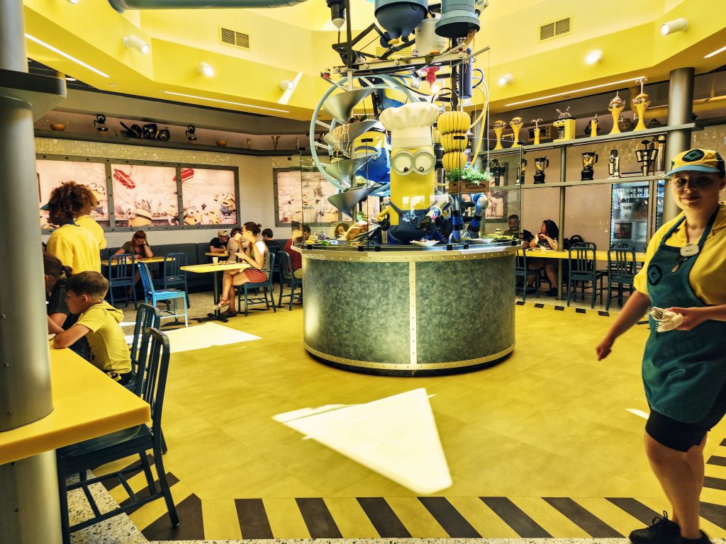 The inside of Minion cafe includes a large exhibit of minions working on food in the center of the dining room.