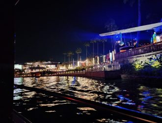 A nighttime view of the City Walk restaurants and waterside seating areas.