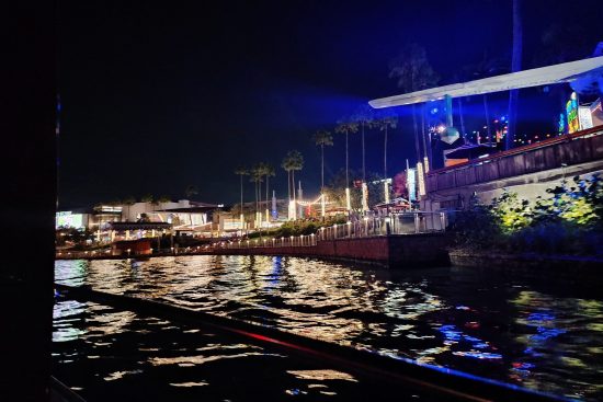 A nighttime view of the City Walk restaurants and waterside seating areas.