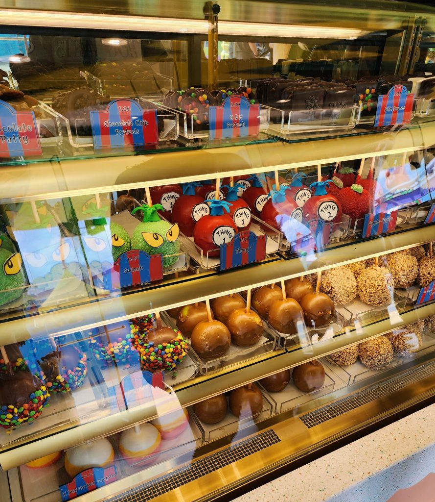 A clear bakery case filled with candied apples, chocolate covered pretzels and chocolate covered smores.