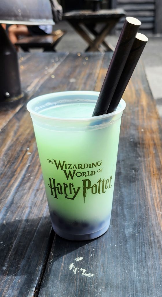 A cup of fishy green ale, a light green colored carbonated beverage with blue popping boba pearls at the bottom.