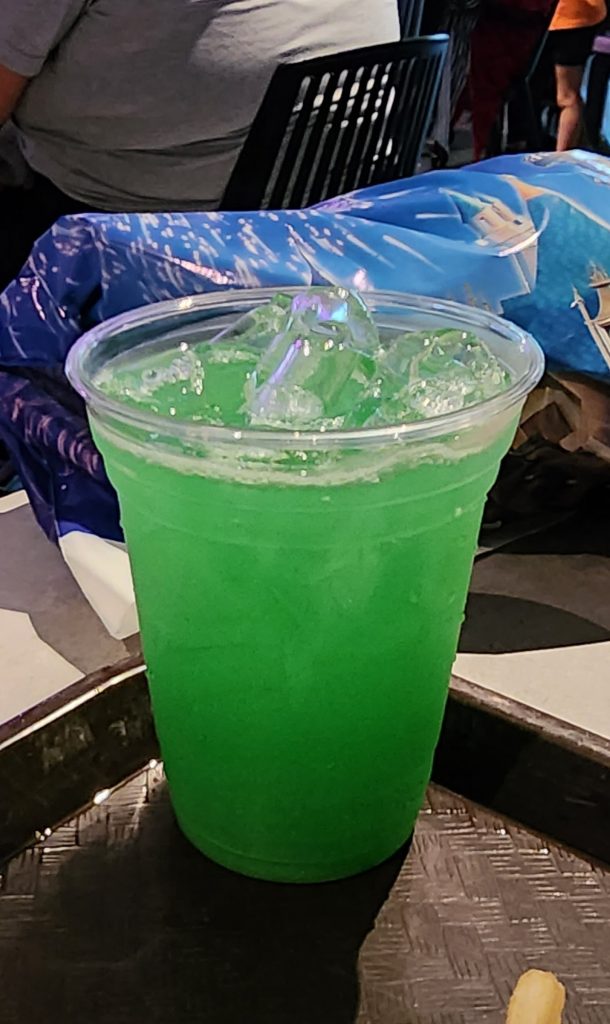 An iced glittery green drink in a clear cup.