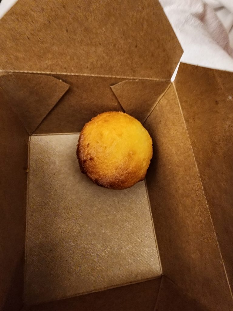 A large container with one lonely small cornbread muffin.