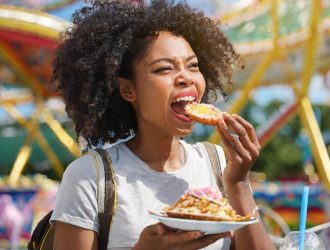 A black woman eating at a theme park.