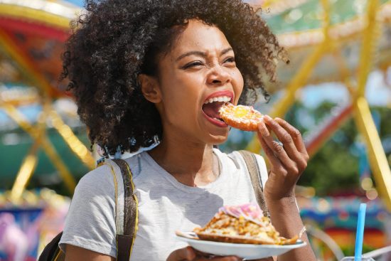 A black woman eating at a theme park.