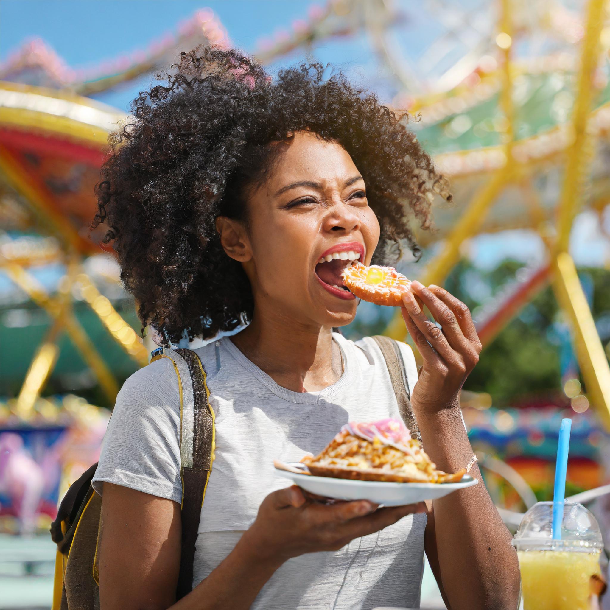 A black woman eating at a theme park.