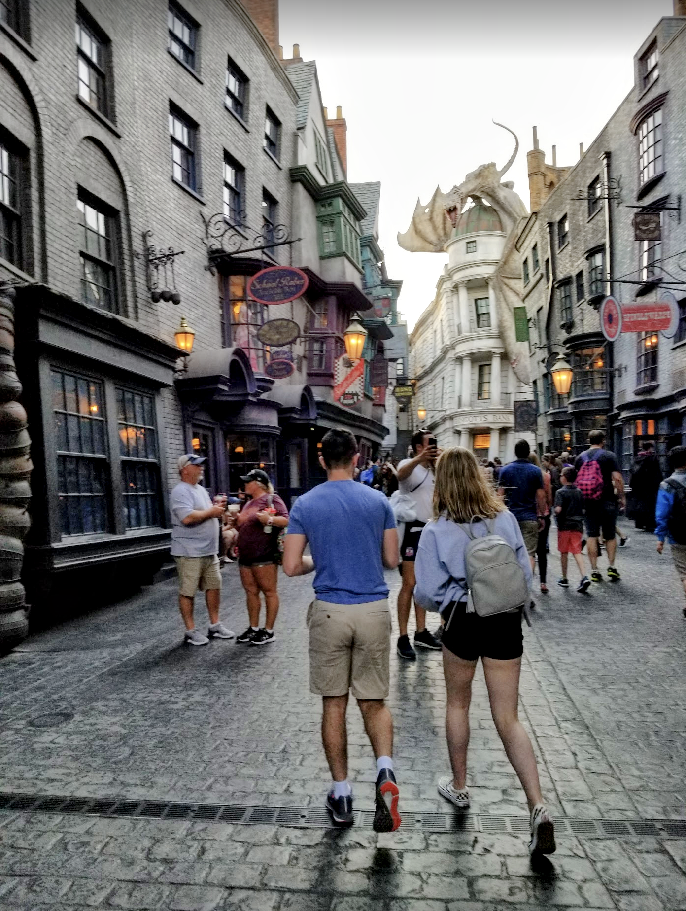 Diagon Alley at Universal Studios Florida: A busy street with colorful shops and awnings, with an animatronic dragon atop a fake bank building.